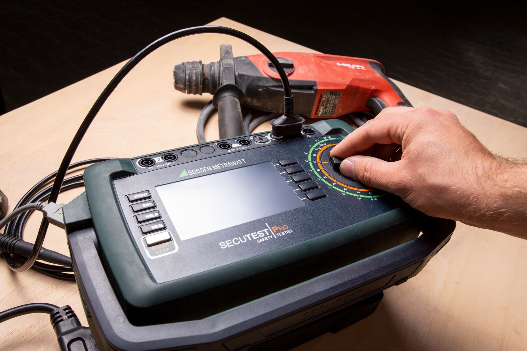 Techniker bedient ein Gossen Metrawatt Sicherheitsprüfgerät neben rotem Elektrowerkzeug